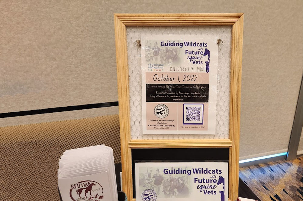 A framed flyer for "Guiding Wildcats, Future Equine Vets" displays an event date of October 1, 2022, with a QR code and logos. Nearby, a stack of brochures with a red horse logo sits on a table.